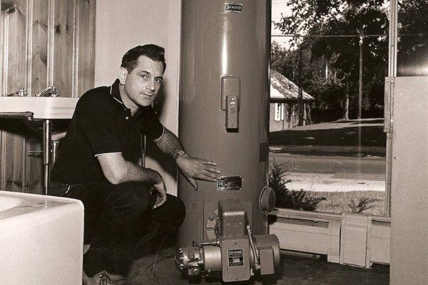 1960s black-and-white photograph of a technician installing a water heater